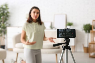 Kadın spor blogcusu evdeki cep telefonunun ekranında video kaydediyor.