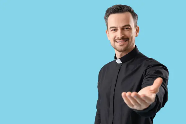 青い背景に手を差し伸べる男性司祭の肖像 — ストック写真