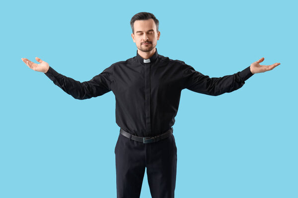Portrait of male priest praying on blue background