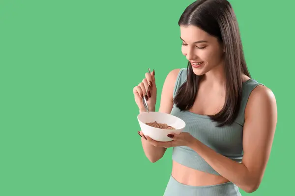 Sportliche Junge Frau Isst Haferflocken Auf Grünem Hintergrund Ernährungskonzept — Stockfoto
