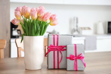 Mutfaktaki Uluslararası Kadınlar Günü için lale ve hediye kutularıyla dolu vazo.