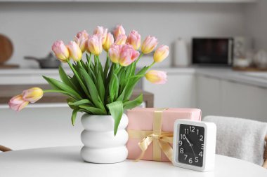 Laleli vazo, Uluslararası Kadınlar Günü için hediye kutusu ve mutfaktaki masada saat.