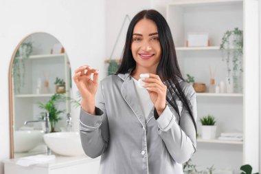 Evdeki banyoda diş ipiyle güzel, genç, mutlu bir kadın.