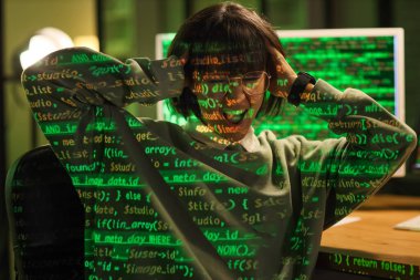 Stresli kadın programcı gece ofiste programlama kodunu yansıtıyor.