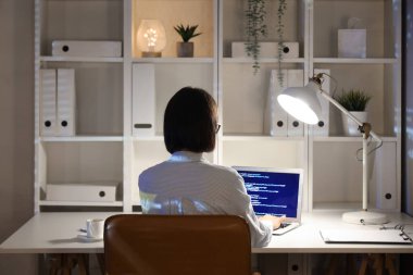 Genç bayan programcı geceleri ofiste dizüstü bilgisayarla çalışıyor.