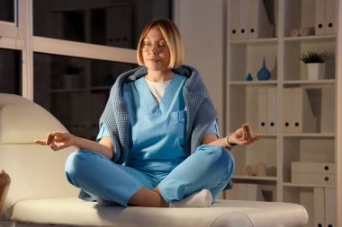 Kadın hemşire akşamları hastanede meditasyon yapıyor.