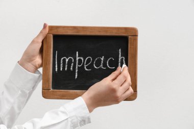 Woman writing word IMPEACH on chalkboard against white background clipart