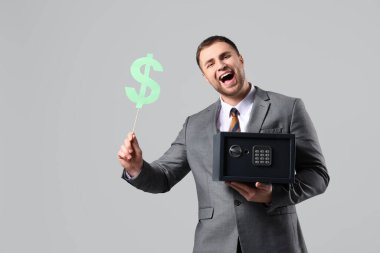 Gri arka planda kasası ve kağıt dolar işareti olan mutlu genç adam.