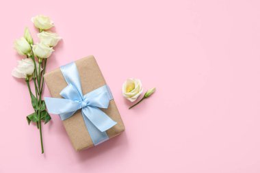 Pembe arka planda güller olan güzel paketlenmiş hediye kutusu