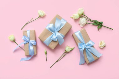 Pembe arka planda güllerle süslü hediye kutuları.