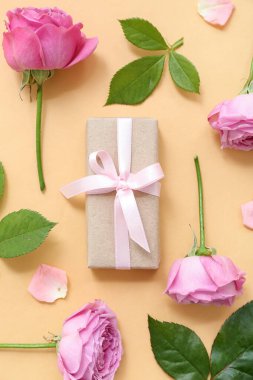 Sarı arka planda güller olan zarif paketlenmiş hediye kutusu.