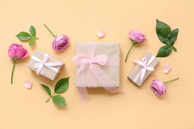 Zarif paketlenmiş, sarı arka planda güller olan hediye paketleri.