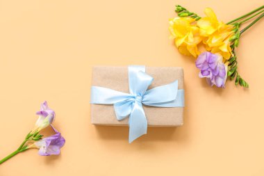 Sarı arka planda çiçekler olan güzel paketlenmiş hediye kutusu.