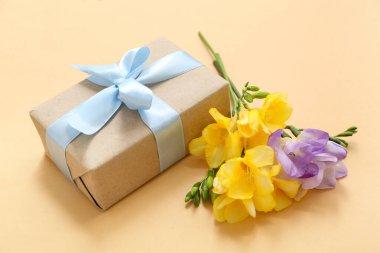 Sarı arka planda çiçekler olan güzel paketlenmiş hediye kutusu.