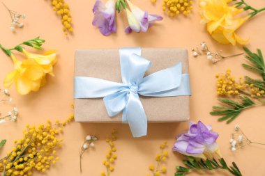 Sarı arka planda çiçekler olan güzel paketlenmiş hediye kutusu.