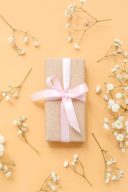 Sarı arka planda çiçekler olan zarif paketlenmiş hediye kutusu.