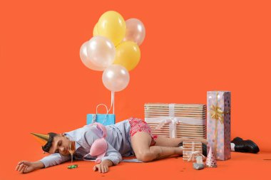 Akşamdan kalma ve turuncu arka planda doğum günü partisinden sonra uyuyan genç bir adam.