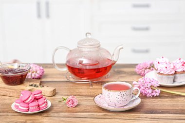 Çaydanlık ve bir fincan amberçiçeği çayı. Mutfaktaki masada tatlılar.