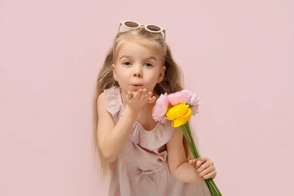 Симпатична Маленька Дівчинка Красивими Квітами Рунункула Дме Поцілунок Рожевому Фоні — стокове фото