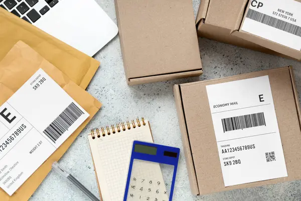 Cardboard packages with labels, envelopes and calculator on white table