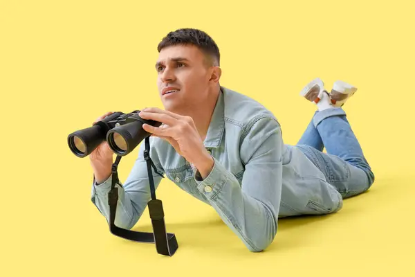 Junger Mann Mit Fernglas Liegt Auf Gelbem Hintergrund — Stockfoto