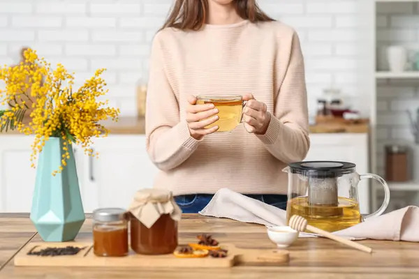 Young woman drinking green tea in kitchen