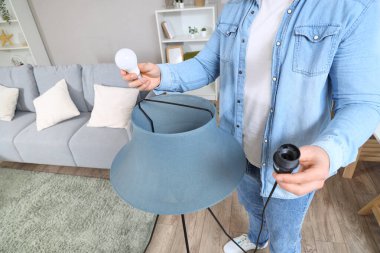 Evdeki modern standart lambada ampulü değiştiren adam, yakın plan.