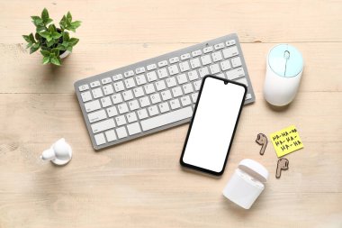 Karton kulaklık, yapışkan not, bilgisayar klavyesi ve ahşap arka planda telefon. 1 Nisan şakası.