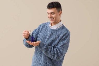 Arka planda bir şişe CBD yağı olan genç bir adam.