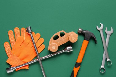 Yeşil arka planda bir takım mekanik aletler, eldivenler ve oyuncak araba. Mekanik kavram