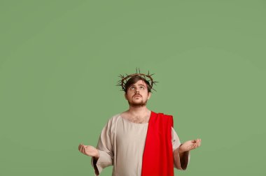 İsa cüppeli bir adam ve dikenli bir taç, yeşil arka planda uzanan eller
