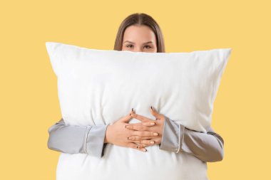 Sarı arka planda yumuşak yastıklı genç kadın