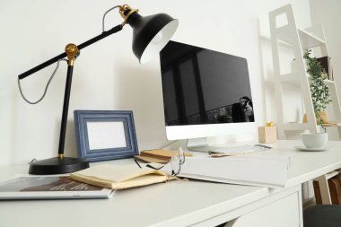 Ofisinde bilgisayar, lamba ve bardak olan modern işyeri