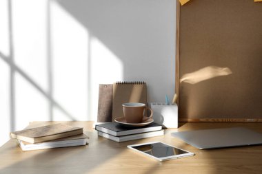 Açık ofiste kitapları, fincanı ve dizüstü bilgisayarı olan işyeri