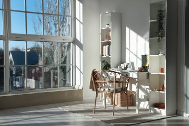 Çalışma yeri, penceresi, raf ünitesi ve ev bitkisi olan şık bir ofis.