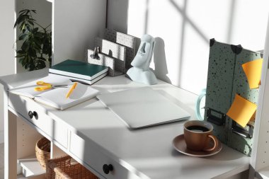 Ofisinde defter, dizüstü bilgisayar ve bir fincan kahve olan modern bir iş yeri.