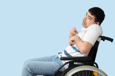 Mavi arka planda tekerlekli sandalyedeki genç adam. Ulusal Beyin Felci Farkındalığı Ayı