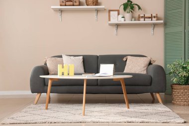 Siyah kanepesi, masası ve rafları olan rahat oturma odasının modern iç mekanı.