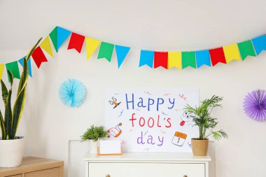 Oturma odasındaki çekmecelerde Mutlu Ahmaklar Günü yazılı bir poster.