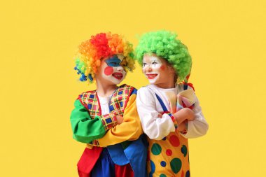 Sarı arka planda palyaço kostümlü komik çocuklar. 1 Nisan Kutlaması