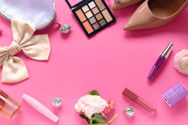 Pembe arka planda yay, yaka çiçeği ve makyaj ürünleri olan kadın balo ayakkabılarından yapılmış çerçeve.