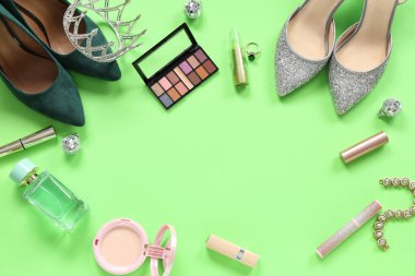 Yeşil arka planda taç ve makyaj ürünleri olan kadın balo ayakkabılarından yapılmış çerçeve