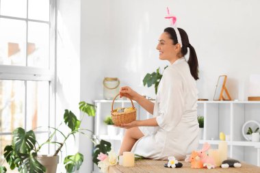 Tavşan kulaklı ve paskalya yumurtalı genç bir kadın spa salonunda oturuyor.