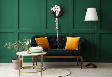 Şık oturma odasının içinde kanepe, masa ve Paskalya çelengi var.