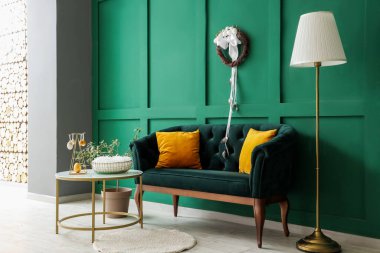 Şık oturma odasının içinde kanepe, masa ve Paskalya çelengi var.