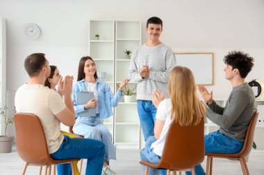 Grup terapisinde ellerini çırpan gençler.