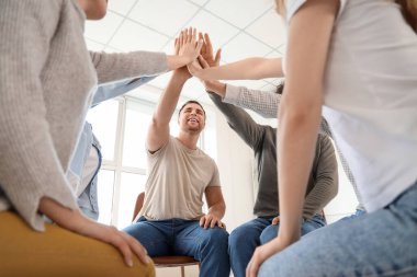 Gençler grup terapisinde ellerini birleştiriyor.