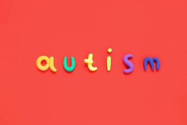 Kırmızı arkaplanda renkli sözcük AUTISM