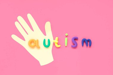 Pembe arka planda kağıt el ve kelime AUTISM. Otistik bozukluk kavramı