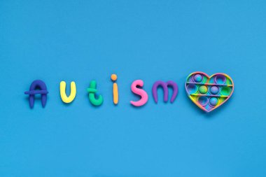 Plastik kelime AUTISM ve mavi arka planda patlat